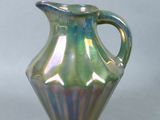 a green glass vase with a handle on a table