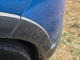 a cat that is laying under the tire of a blue car