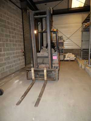un chariot élévateur au milieu d'une pièce remplie de palettes
