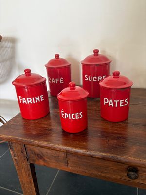 cinq bidons rouges posés sur une table en bois