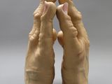 clay sculpture of two hands holding each other in front of a gray background