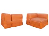 pair of orange leather lounge chairs with ottomans on white background