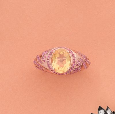 une image représentant une bague ornée d'une pierre jaune entourée de diamants roses et blancs