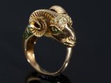 un gros plan d'une bague en or ornée d'une tête de bélier