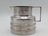 an antique silver plated milk jug with a handle