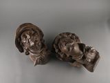 pair of carved busts of two men with hats on each of them