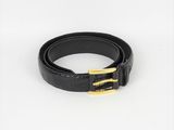 une ceinture noire ornée d'une boucle dorée sur fond blanc