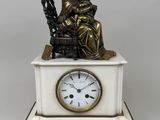 une statue représentant une femme assise sur un banc, avec une horloge