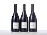 three bottles of wine are lined up on a table