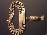 a gold chain and a silver bracelet on a black surface