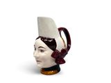 un mug en céramique en forme de tête de femme coiffée d'un chapeau
