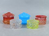 quatre récipients en verre de couleurs différentes posés les uns à côté des autres sur une surface blanche