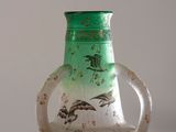 un vase en verre vert orné d'un motif représentant des oiseaux