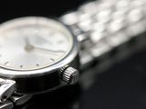 a close up of a silver watch on a black surface