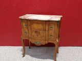 an old wooden chest of drawers with marble top against a red wall