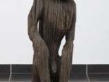 une sculpture en bois représentant un homme assis sur une souche d'arbre