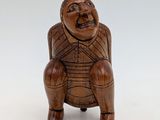 an image of a small wooden figurine of a man sitting on a stool