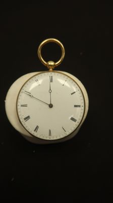 a small white clock with roman numerals on it