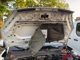 a broken car with the hood open and a broken bike in the trunk