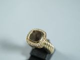 un gros plan d'une bague en or sertie d'une pierre marron