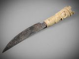a close up of a knife on a table with a gray background