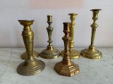 four brass candlesticks sitting on a marble table