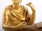 a gold statue of a man holding a cigarette