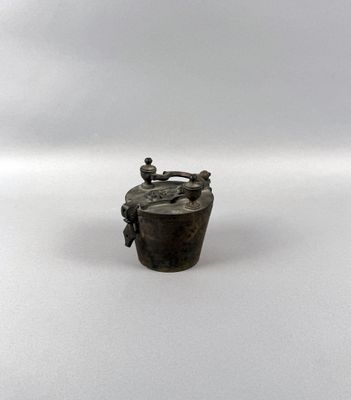 a small metal container with a handle on a white surface