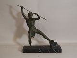 bronze statue of a man holding a spear and shield on a marble base