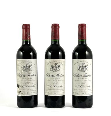 trois bouteilles de vin rouge posées l'une à côté de l'autre sur une surface blanche