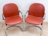 pair of red leather chairs with chrome steel legs and arms