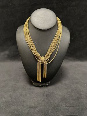 a gold necklace with a tassel on a mannequin neck
