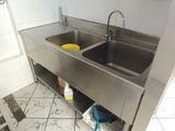 two sinks in the kitchen with a trash can underneath them