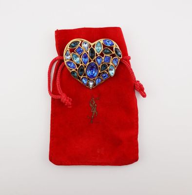 a red velvet bag with a heart shaped brooch on it