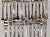 a lot of forks arranged in a row on a table