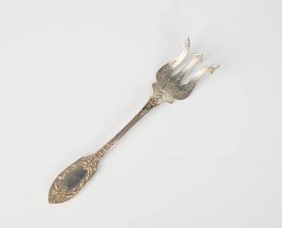 une cuillère en argent surmontée d'une fourchette, posée sur une surface blanche