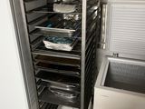 a metal rack with trays of food inside of it