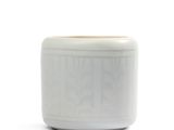 un vase blanc bordé de brun, posé sur une surface blanche