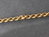 a close up of a gold chain on a gray surface