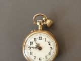 une montre de poche en or à laquelle est suspendue une chaîne sur le côté