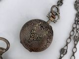 a silver pocket watch with a chain around it