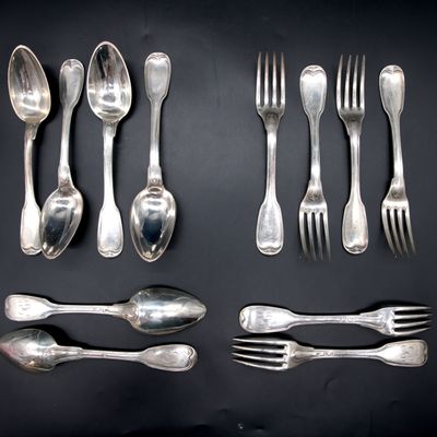 a lot of silver spoons and forks laid out on a table