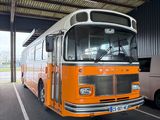 un bus orange et blanc garé sur un parking à côté d'une camionnette blanche