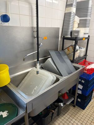 une cuisine équipée d'un évier, d'une poubelle et de poubelles