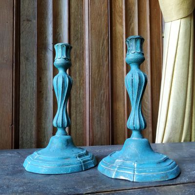 deux bougies bleues posées sur une table devant un rideau