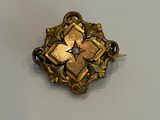 une broche en or ornée d'une fleur sur un fond blanc