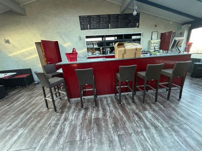 tables and chairs in a restaurant with a red counter and a menu on the wall