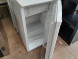 a small white refrigerator sitting in the corner of a room