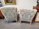 pair of upholstered chairs in a room with a picture on the wall