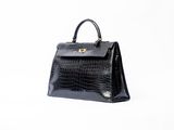 a black crocodile skin handbag on a white background